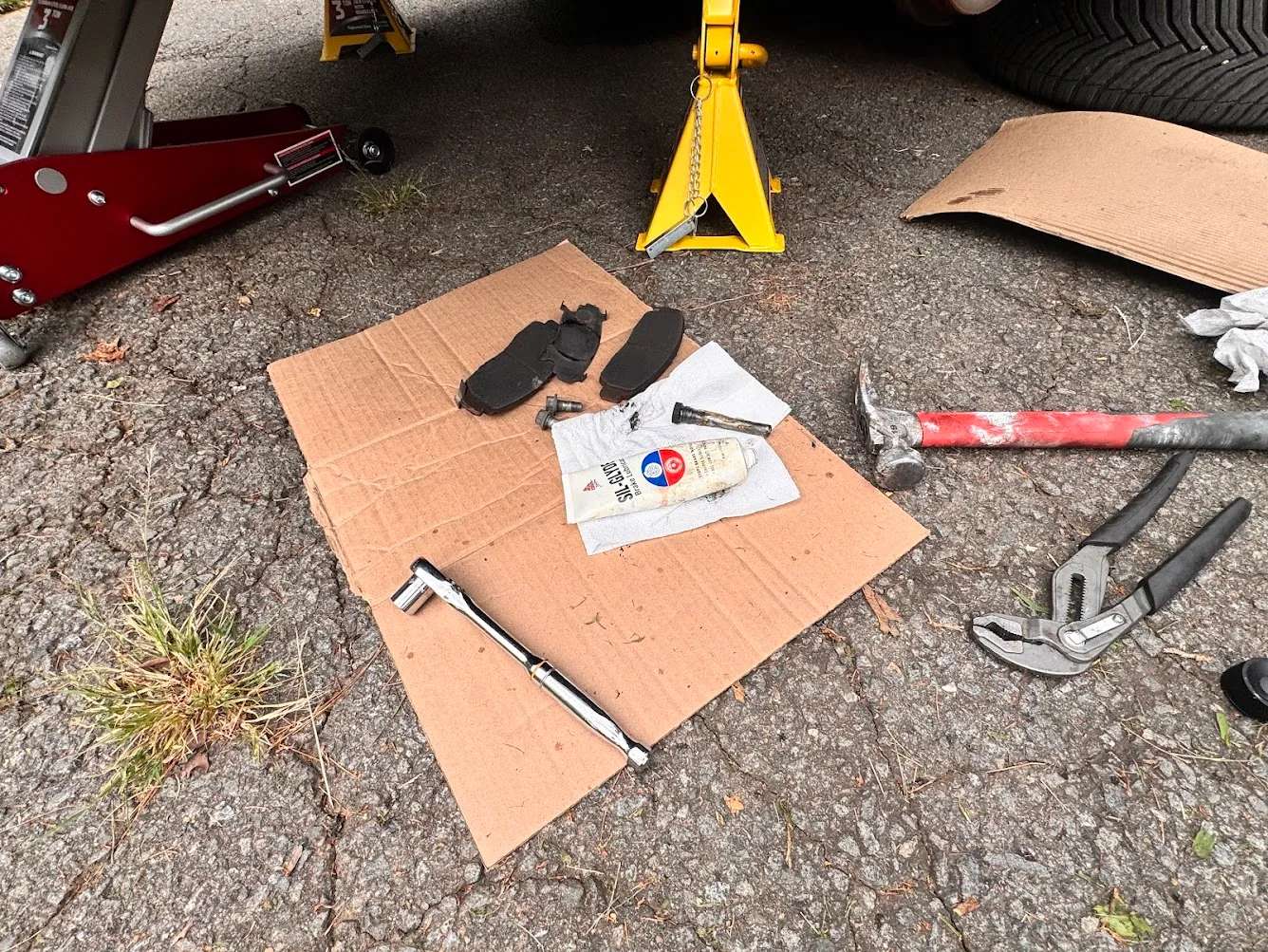 Brake pads, SIL-Glyde, ratchet, tools, cardboard and paper towels during a Honda Accord brake job