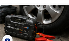 Portable jump starter next to a car tire.