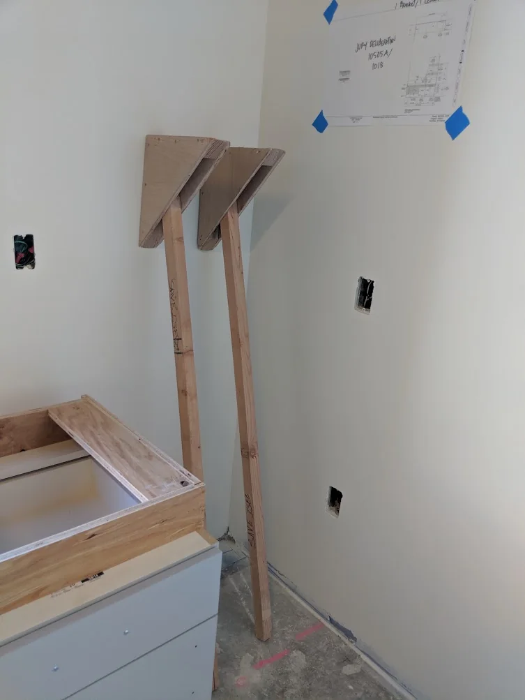 Temporary support brace made from wood on a cabinet installation job